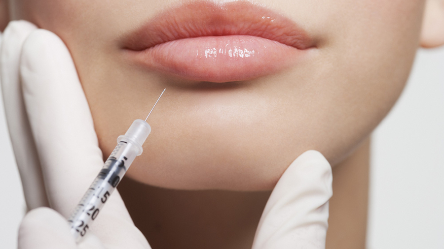 Close up of woman receiving botox injection in lips